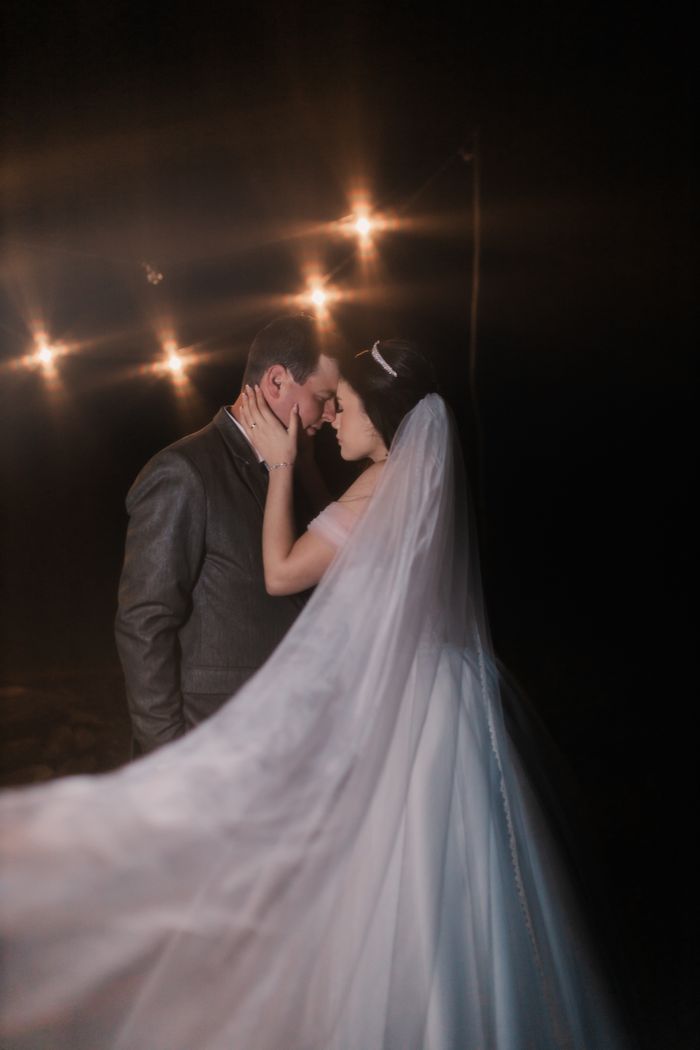 Bride and groom sharing a tender moment under warm lights, creating a dreamy wedding atmosphere.